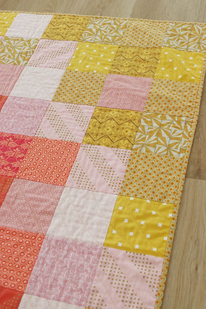 an orange and pink quilt on the floor