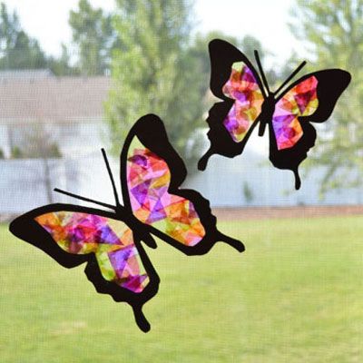 two stained glass butterflies sitting on top of a window sill in front of a grass field