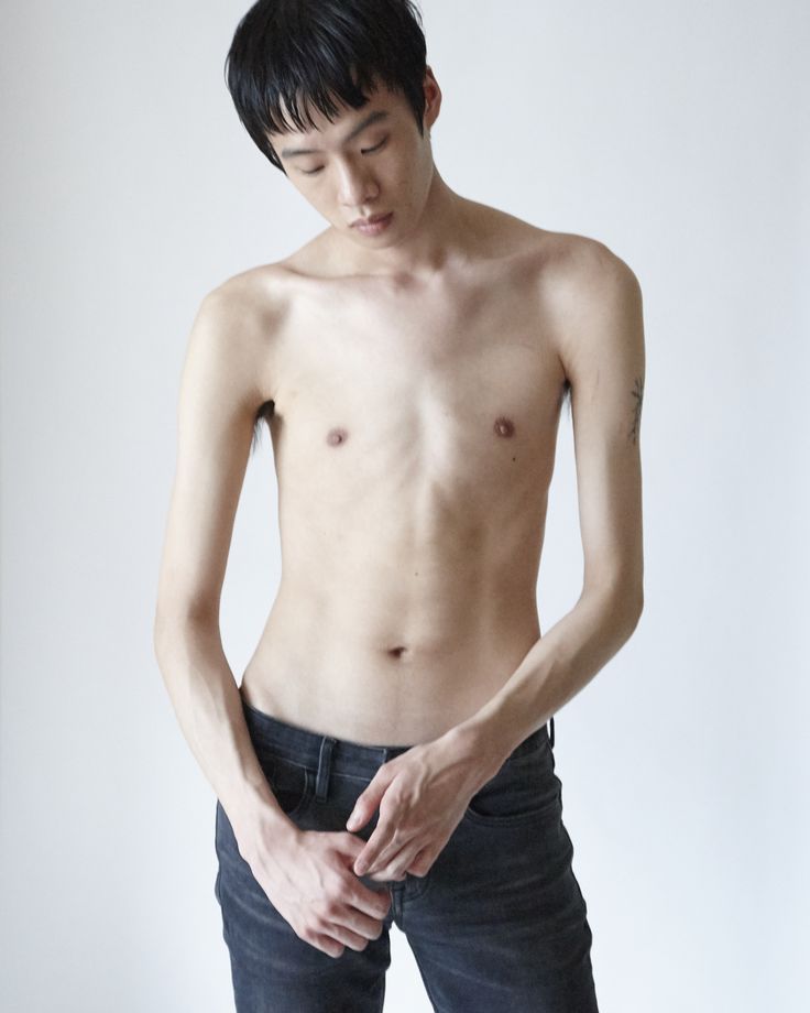 a shirtless young man holding his stomach