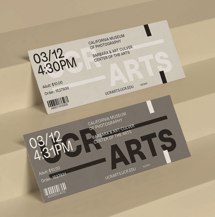 two tickets are sitting on top of each other in front of a beige background with black and white lettering