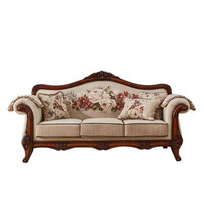 an old fashioned couch with floral pillows on the armrests and back cushiones