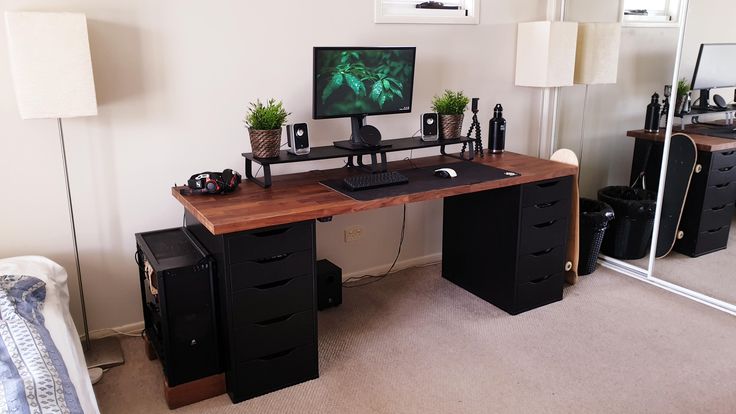 a desk with a computer monitor and keyboard on it in front of a large mirror