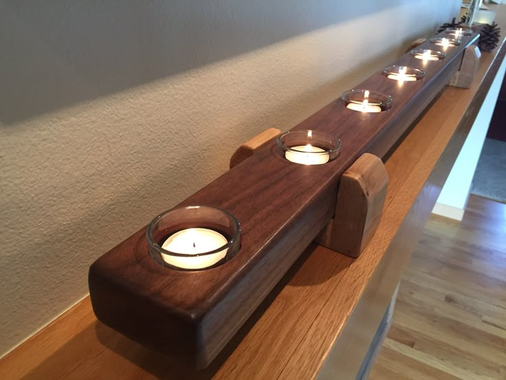 a row of candles sitting on top of a wooden shelf next to a wall and window