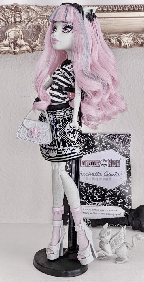 a doll with pink hair is standing in front of a mirror and holding a purse