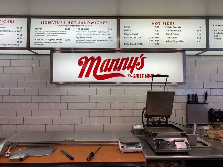 the menus for many different types of sandwiches are hanging on the wall above the counter