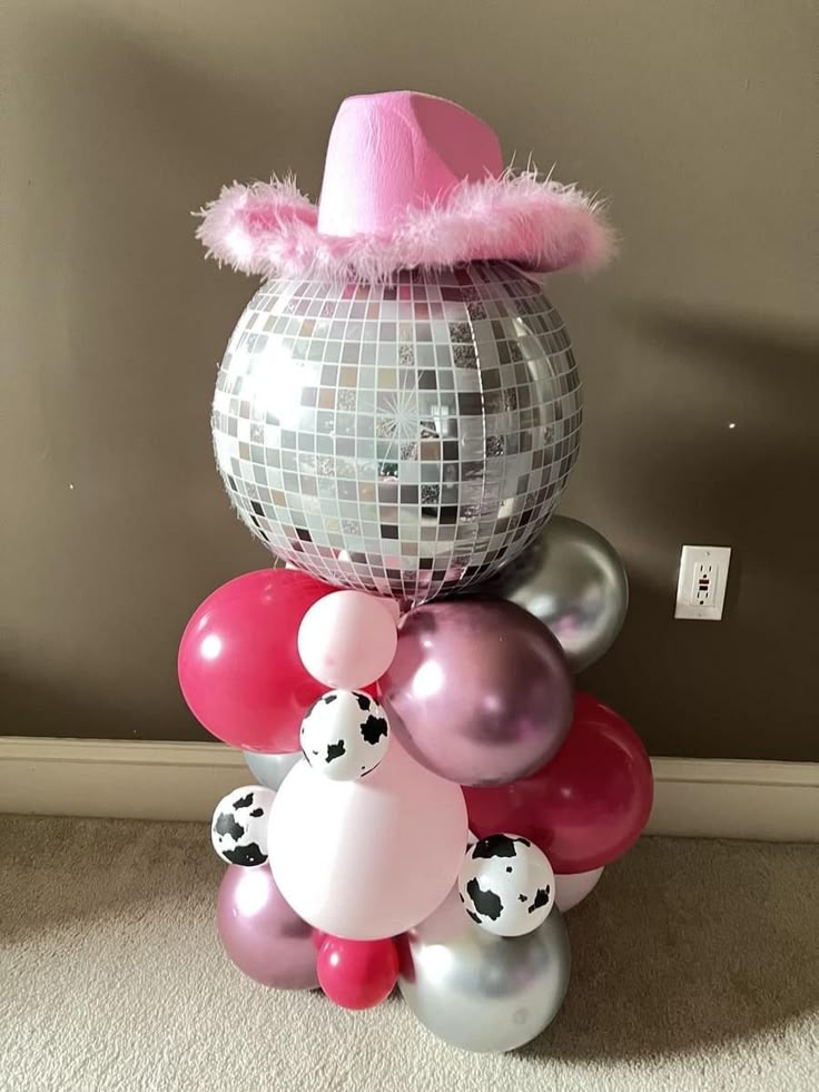 a bunch of balloons that are in the shape of a disco ball with a pink hat on top