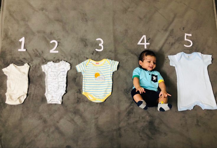 a baby sitting on the floor next to five ones that are numbered in different colors