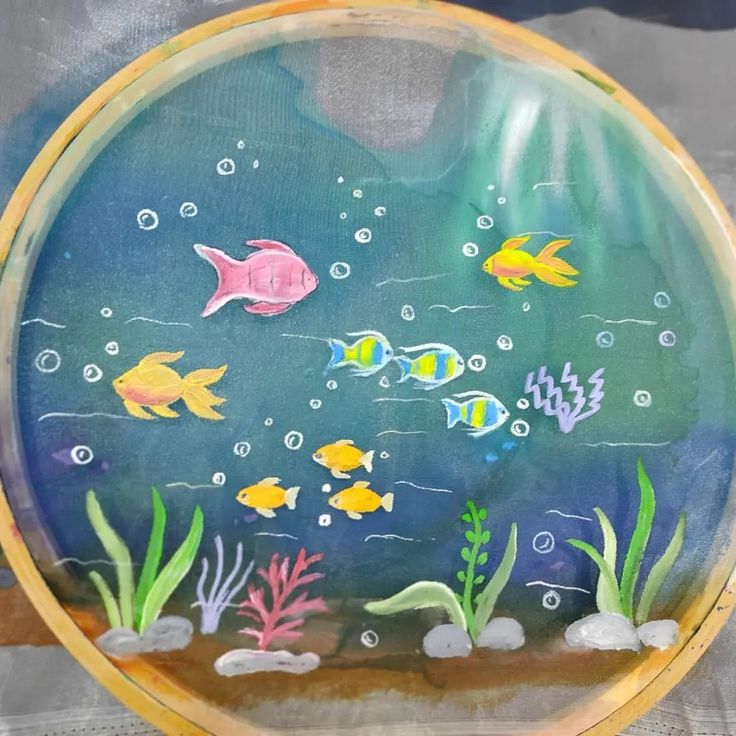 a painted glass plate with fish and bubbles on the bottom is sitting on a table