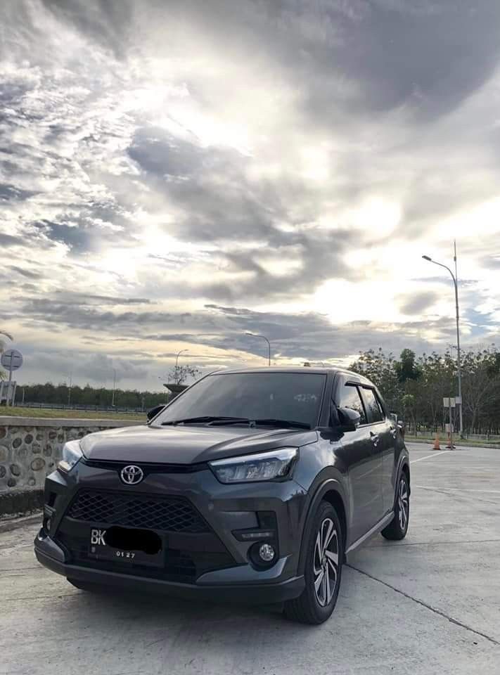 the front end of a gray toyota suv parked in a parking lot with cloudy skies