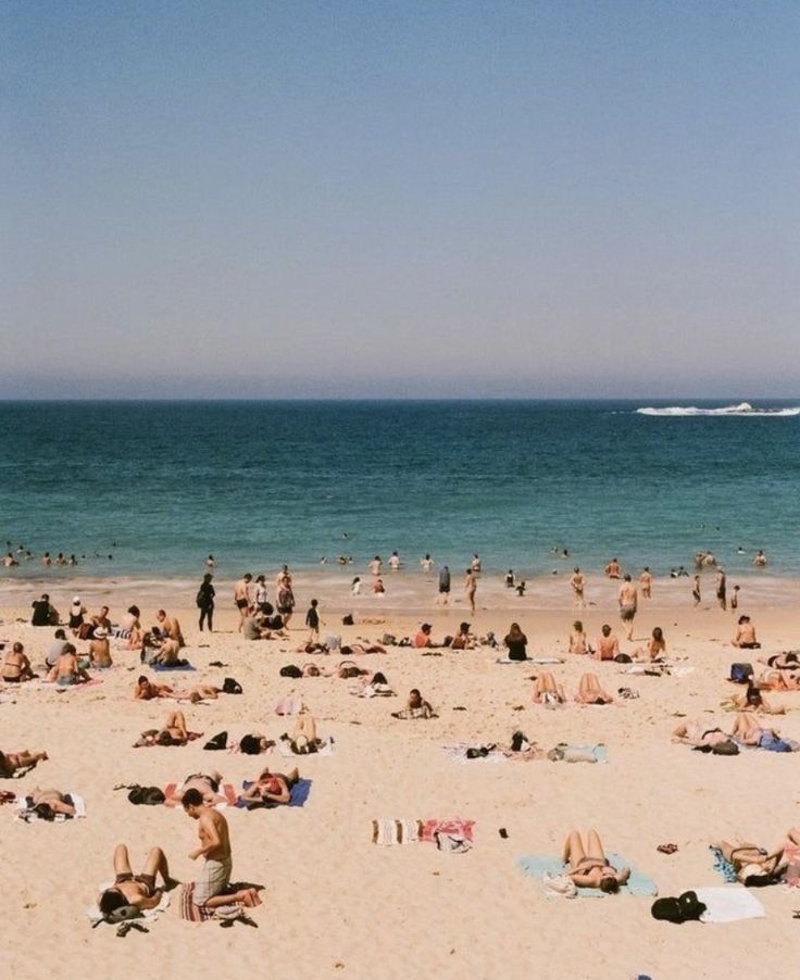 many people are on the beach and one is flying a kite in the sky above them