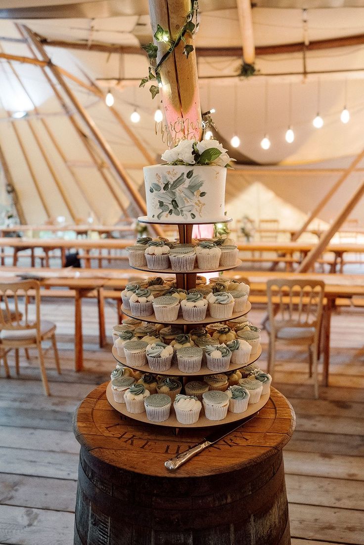 a wedding cake and cupcakes are stacked on top of each other in a tent