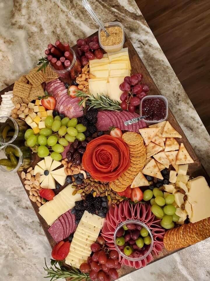 an assortment of cheeses, crackers and grapes on a platter