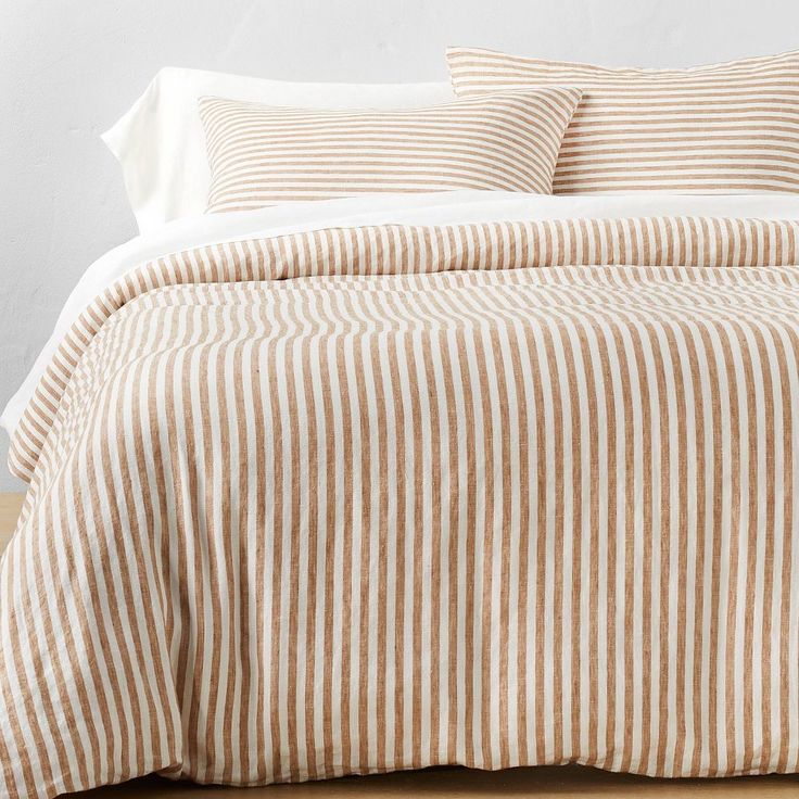 the bed is made with striped linens and has two pillows on top of it