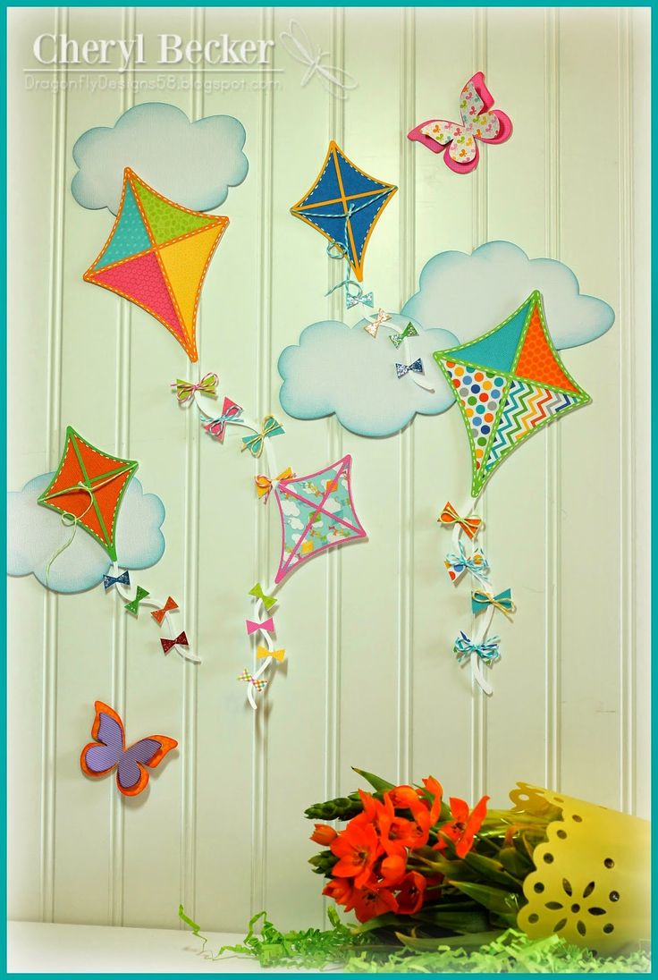 colorful kites are hanging on the wall next to some flowers and butterfly decorations in a vase