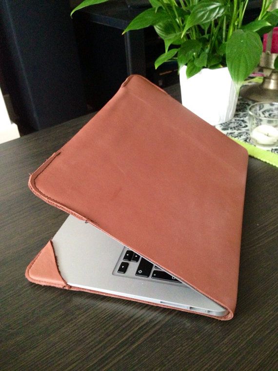 an open laptop computer sitting on top of a wooden table next to a potted plant