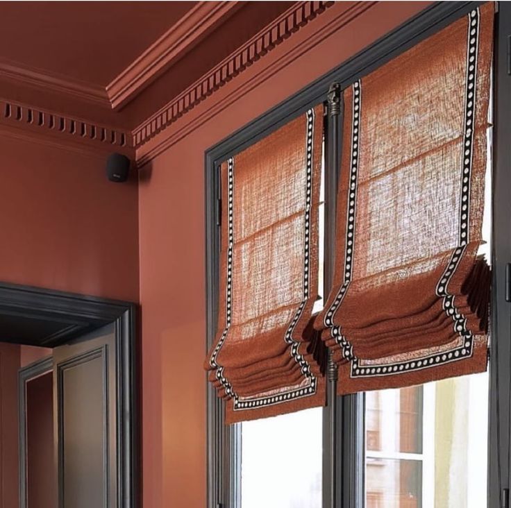 a window with roman blinds in an orange room