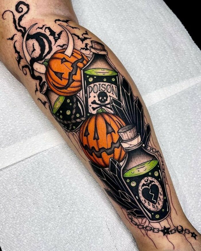 a man's leg with halloween themed tattoos on it and an orange pumpkin in the jar