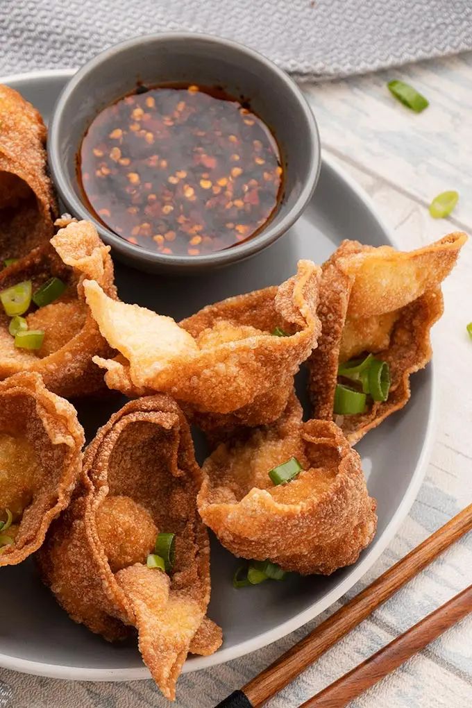 some fried food is on a plate with chopsticks next to it and a bowl of dipping sauce