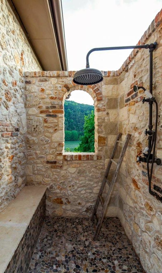 a bathroom with stone walls and an open window in the wall, next to a shower head