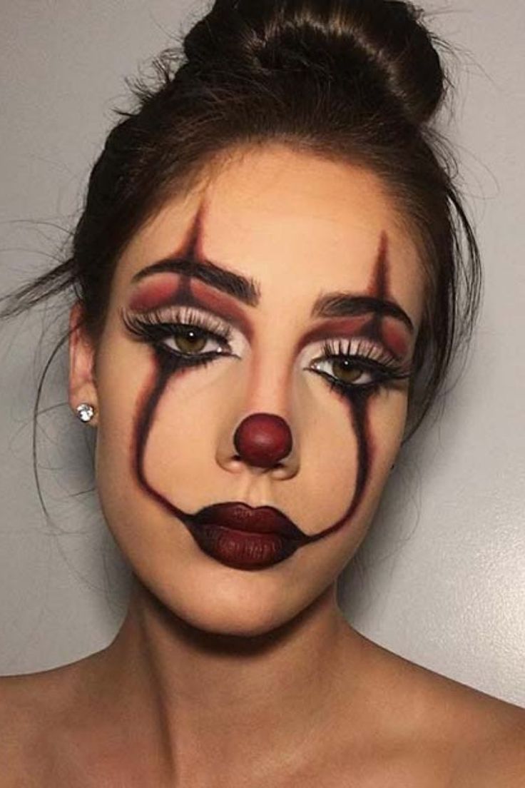 a woman with clown makeup on her face is wearing a red nose and nose ring