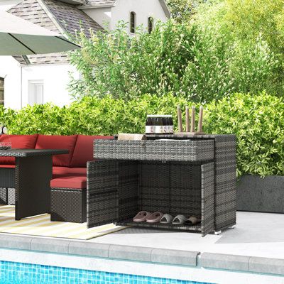 an outdoor patio furniture set next to a swimming pool with trees and bushes in the background