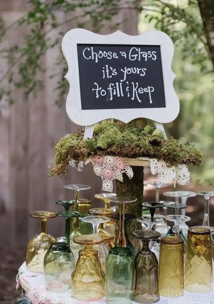 a table topped with lots of vases filled with green plants and moss covered jars