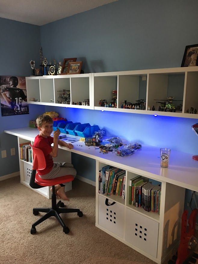 a young boy sitting at a desk in front of a book shelf