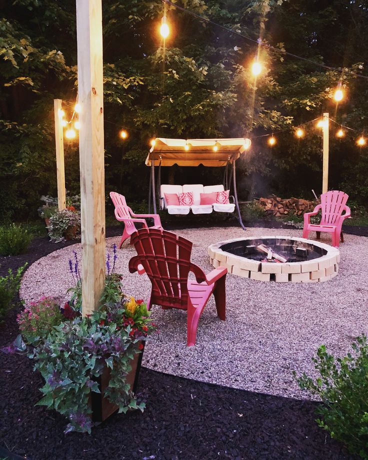 a fire pit surrounded by lawn chairs and lights