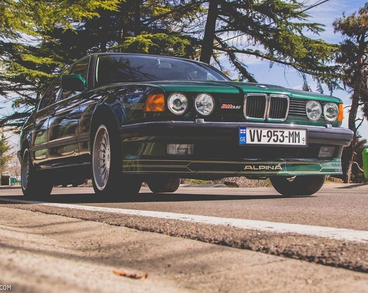 a green car is parked on the side of the road