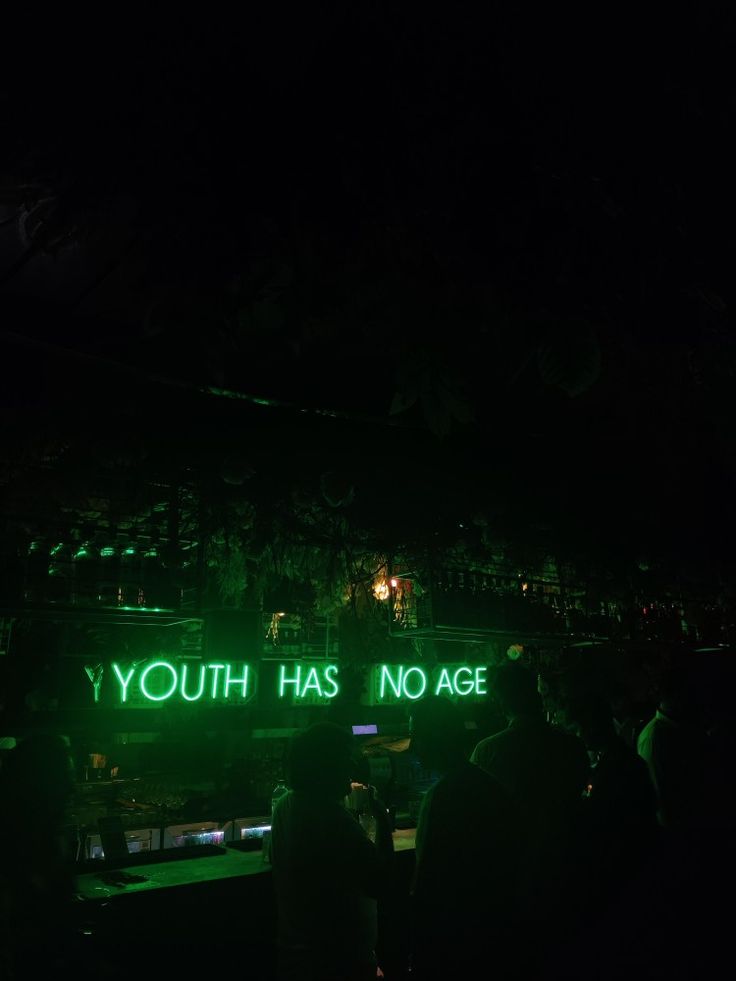 people standing in front of a neon sign that says youth has no age