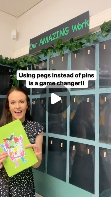 a woman holding up a game changer in front of a wall with the words using pegs instead of pins is a game changer