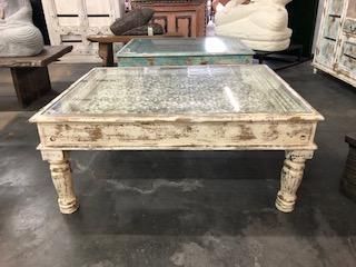 an old coffee table with glass top in a shop