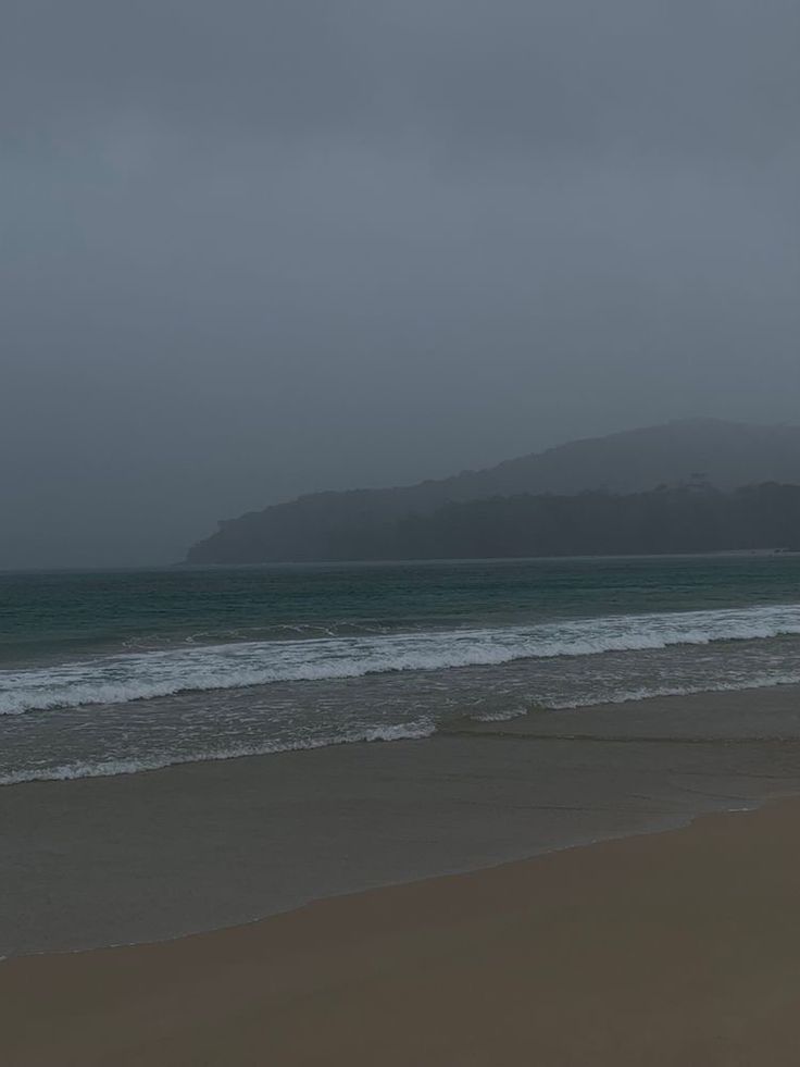 two people walking on the beach with an umbrella