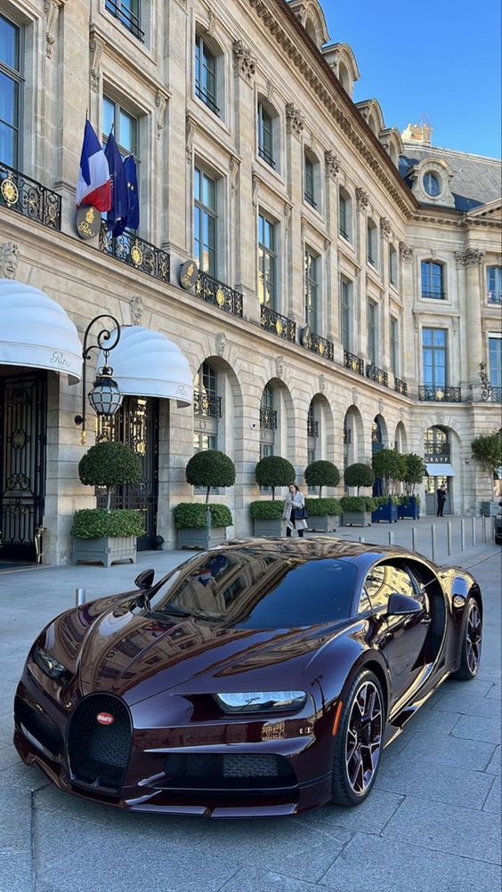 a brown bugatti parked in front of a large building