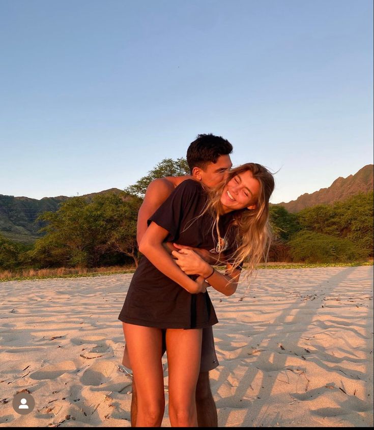 a man and woman are hugging on the beach