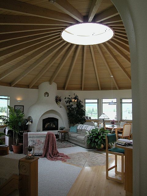 a living room filled with furniture and a fire place under a wooden ceiling mounted dome