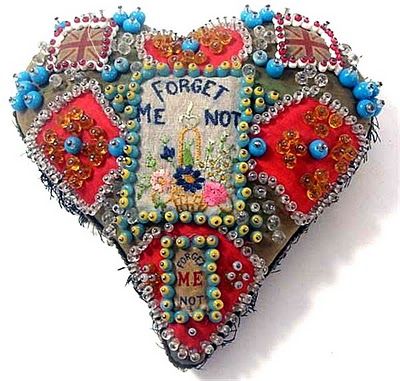 a heart shaped brooch with beaded decorations on it's sides and the words forget me not