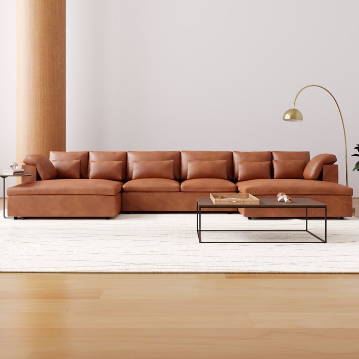 a brown leather couch sitting on top of a wooden floor next to a table and lamp