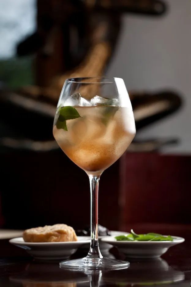 a glass filled with liquid sitting on top of a table next to a plate of food