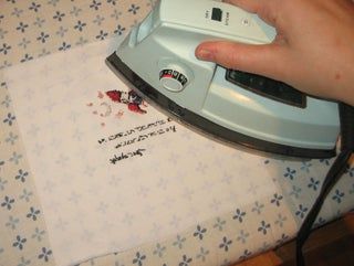 a person ironing fabric with an electric iron on top of a quilted table