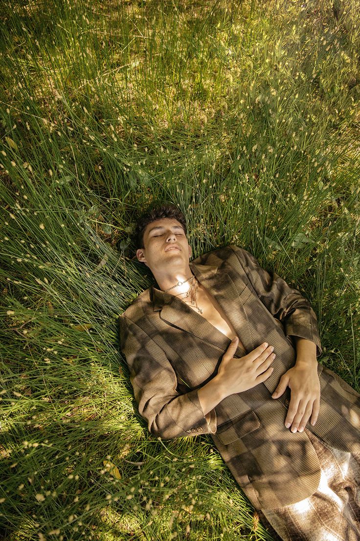 a man laying in the grass with his eyes closed