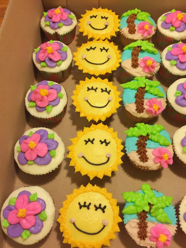 a box filled with lots of cupcakes decorated like flowers and smiley face faces