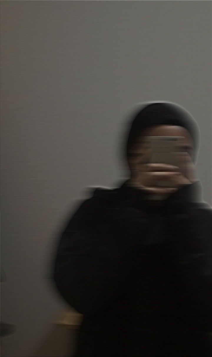 a blurry image of a man holding his cell phone in front of his face