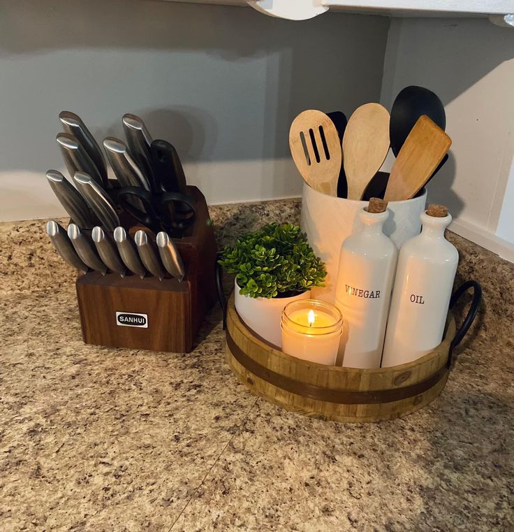 kitchen utensils and candles are sitting in a wooden holder on the counter top