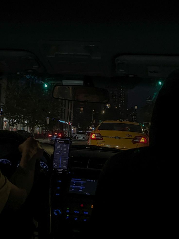 two people sitting in a car with their cell phones up to their ears, and one person driving at night