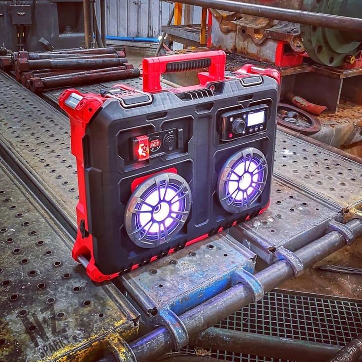 two red and black speakers sitting on top of a piece of metal in a factory