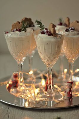 three glasses filled with white wine and garnished with candy canes on a silver tray