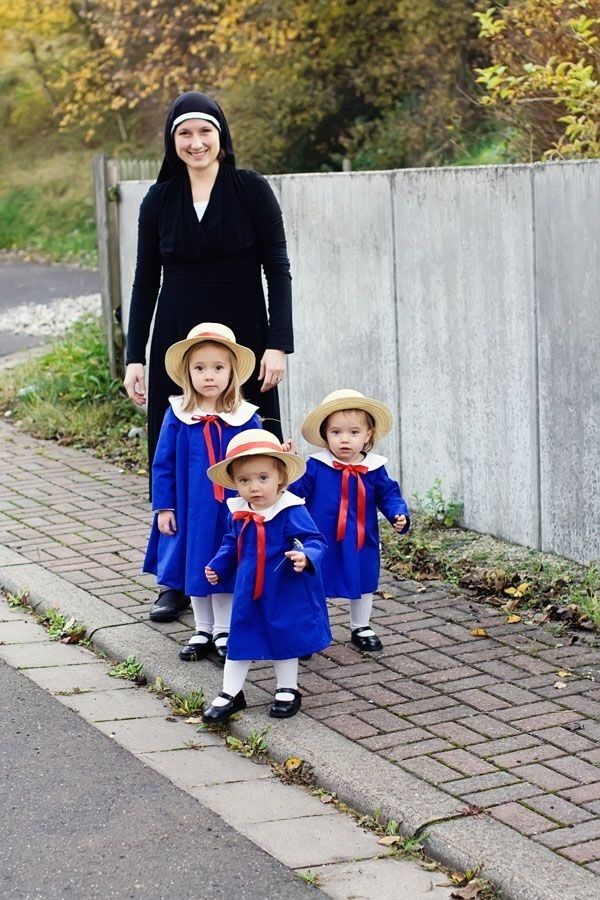 a woman and two children in blue dresses are standing next to each other on the sidewalk