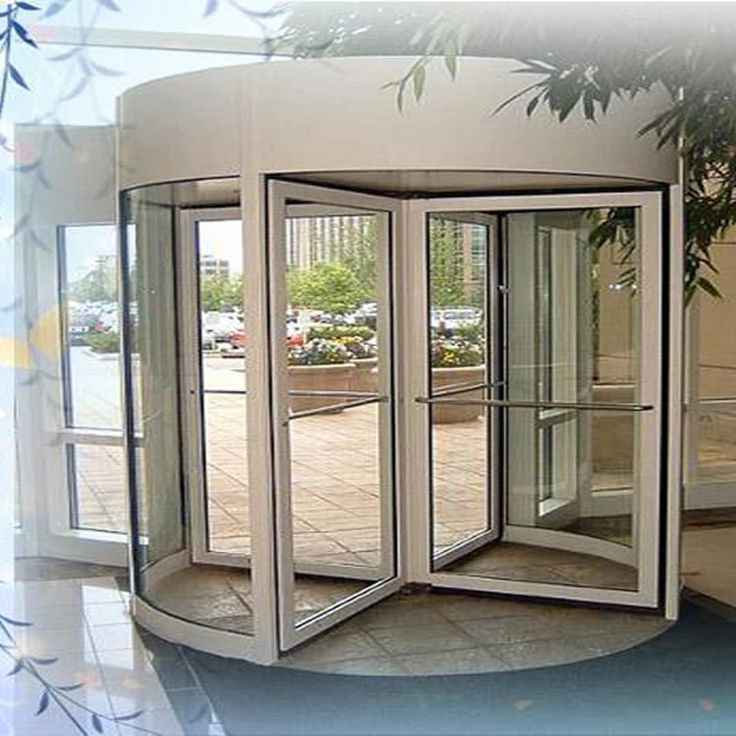 an open room with three revolving doors on the outside and one in the inside, surrounded by greenery