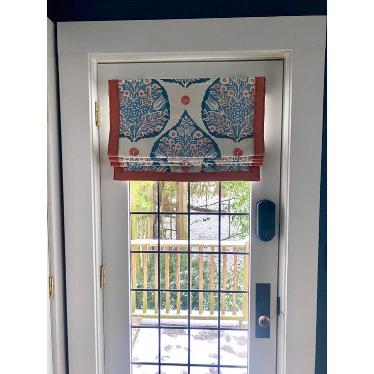 an open door with a window covered in blue and red fabric on the outside wall